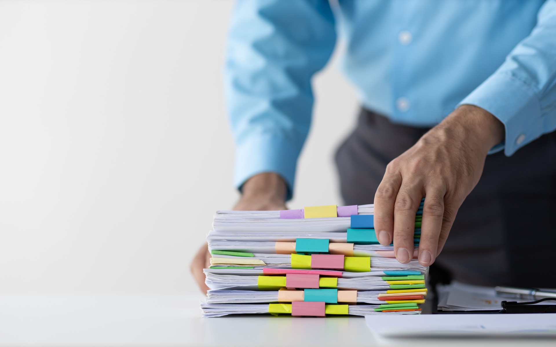 Businessman working in piles of unfinished documents on desk office, business report papers. Auditor checking searching document prepare paperwork or report for analysis.